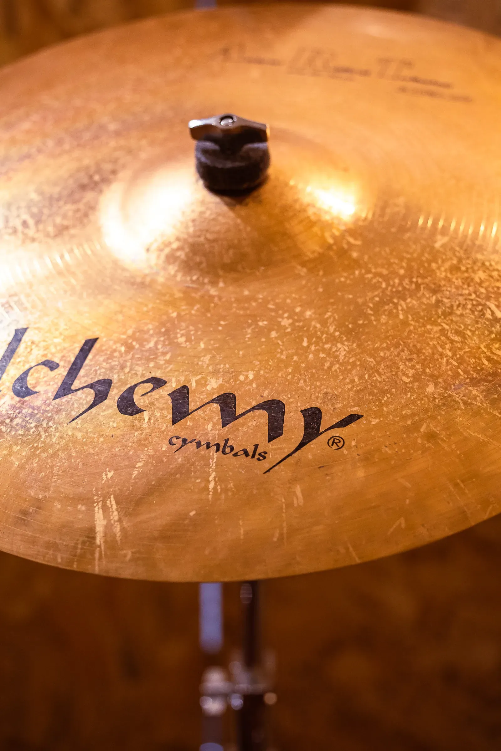 Close-up of an Alchemy cymbal, golden hammered surface with engraved branding, shallow focus, Lyon
