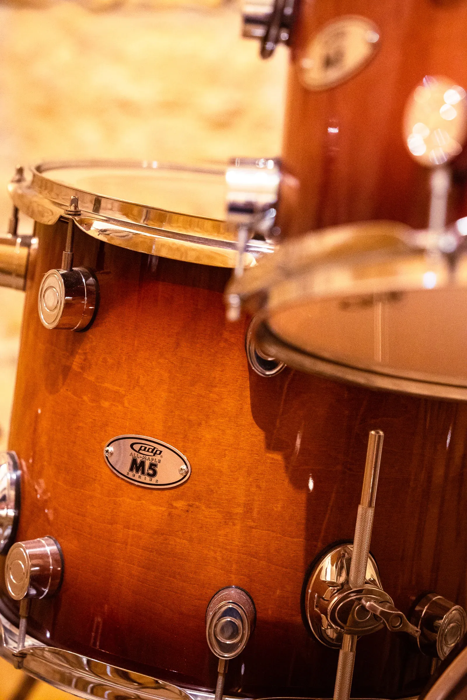 Two PDP M5 toms side by side, chrome lugs and tension rods in warm light, Lyon