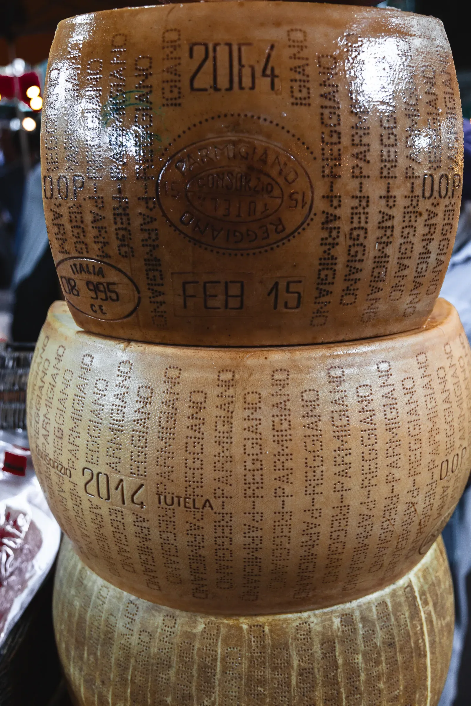 Two stacked wheels of Parmigiano-Reggiano DOP cheese, years 2064 and 2014 stamped into the rind, at a Borough Market stall