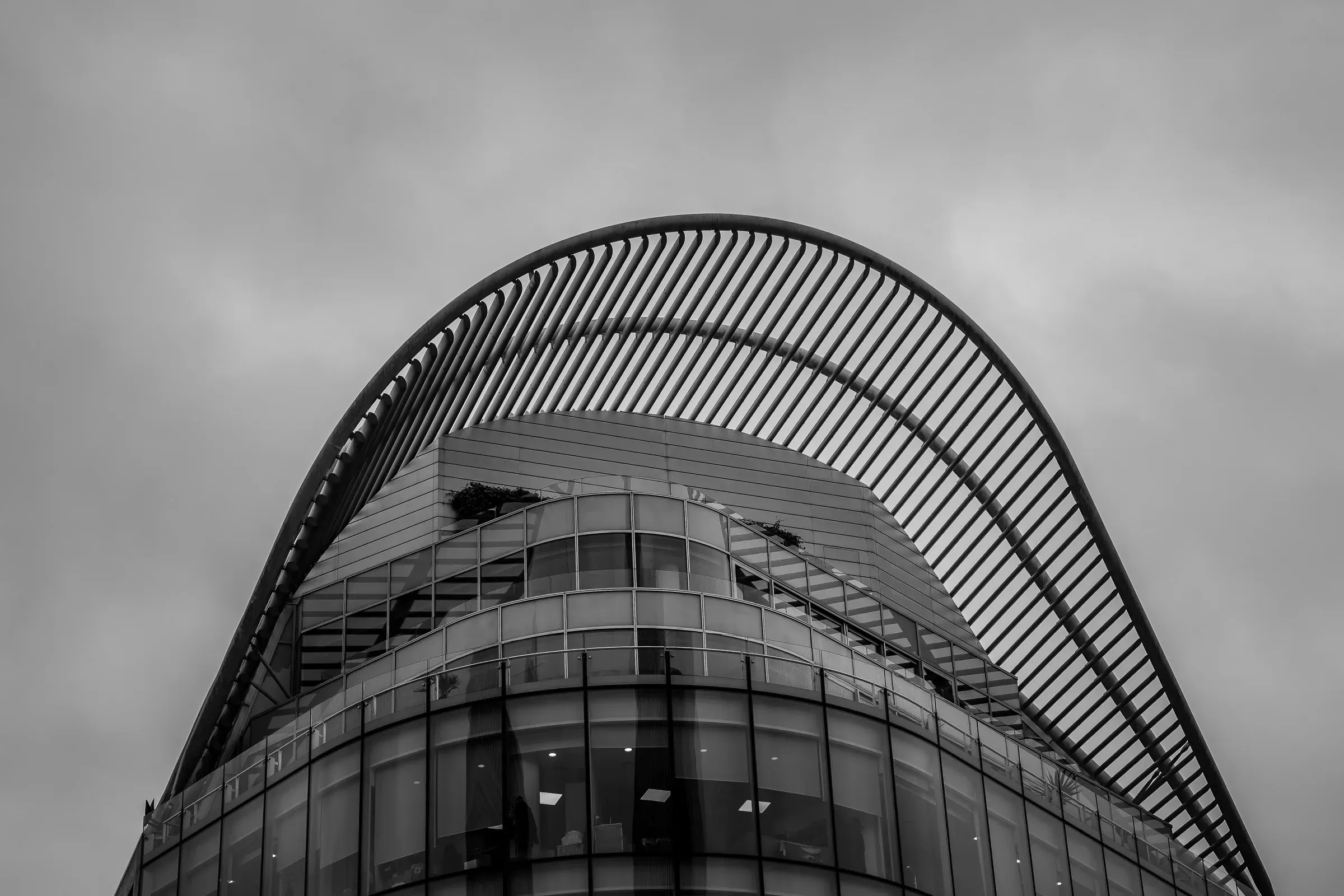 Arched glass and steel canopy over a curved office building, black and white