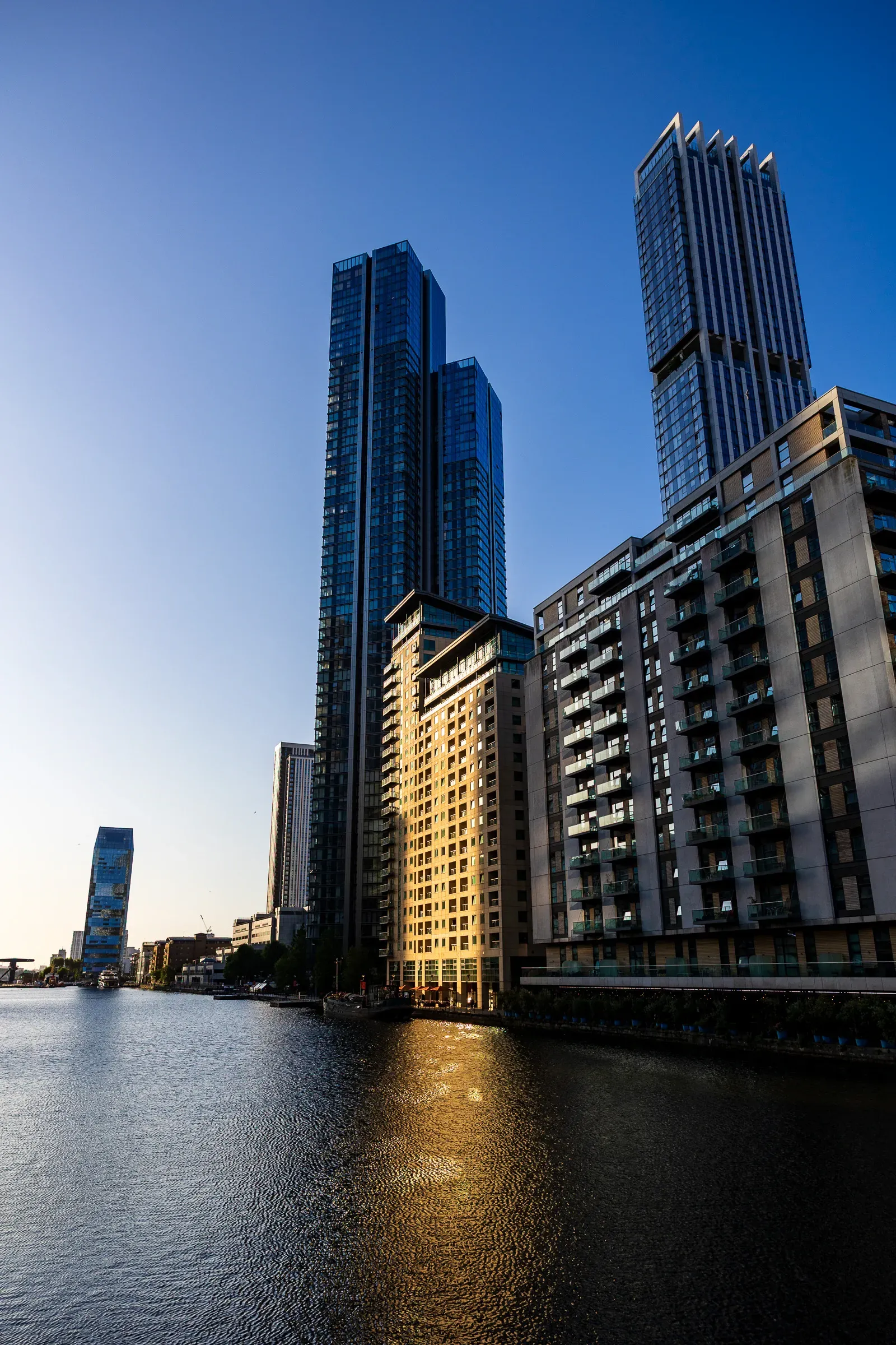 Canary Wharf towers catching the last sunlight, reflected in the dock water at dusk