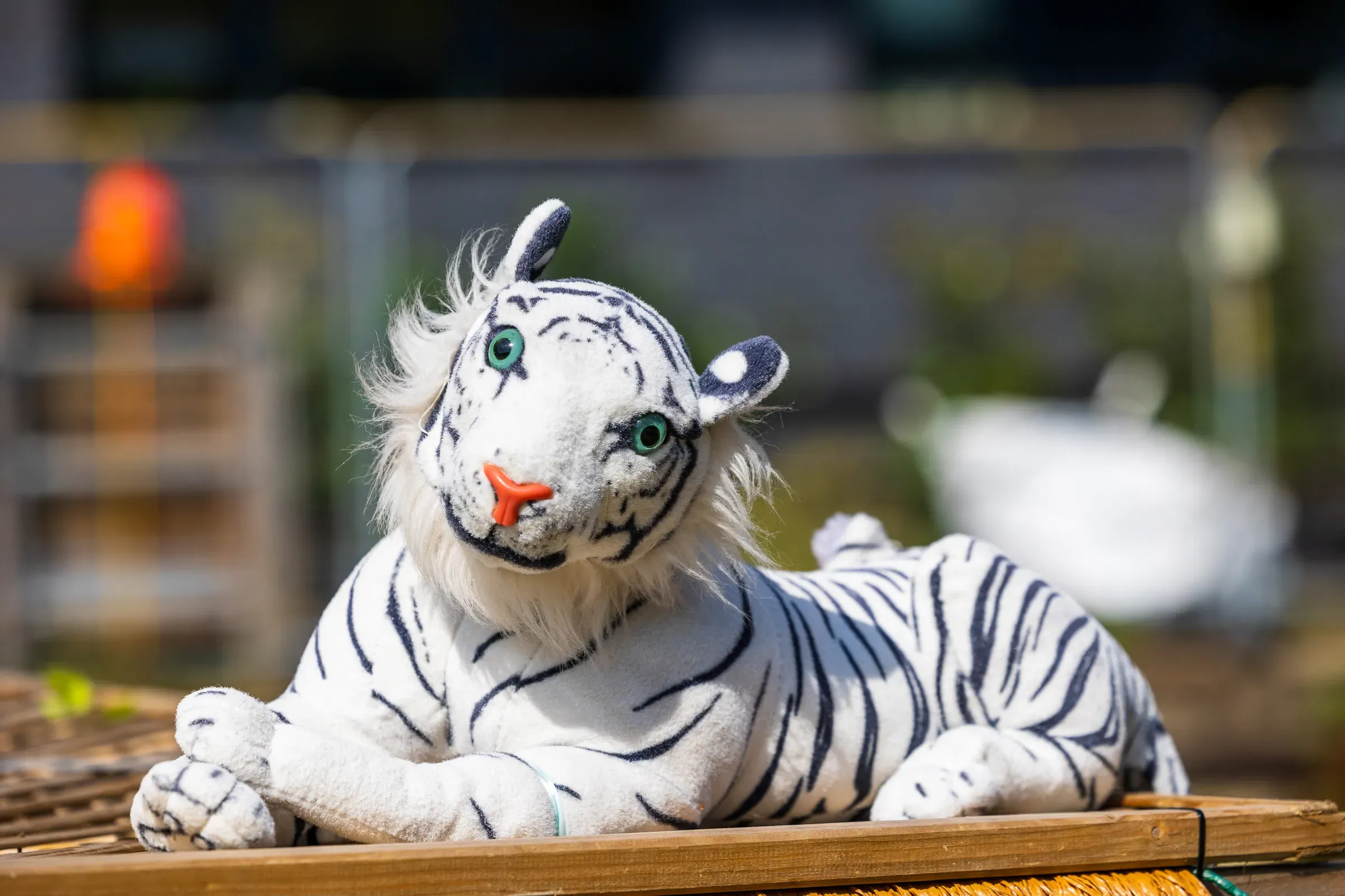 A plush white tiger toy propped on a market stall, blurred stalls behind