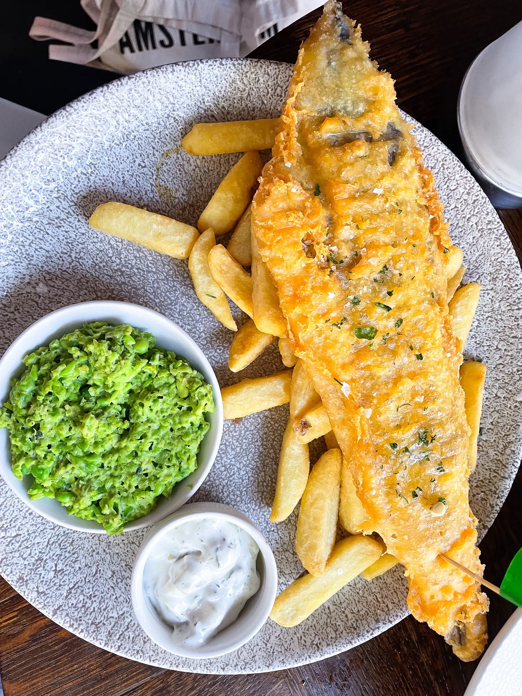 Battered fish and chips with mushy peas and tartare sauce on a plate, overhead view